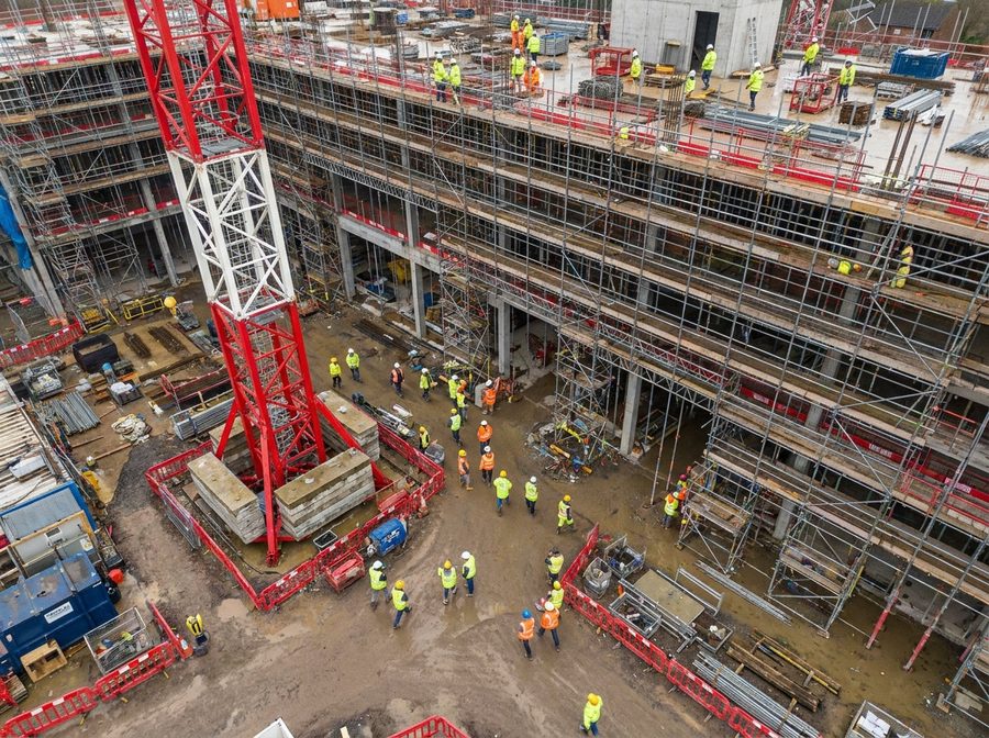 Aerial drone view of an active construction site with crane, scaffolding and workers